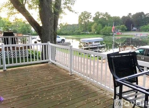 A black chair is on a wooden deck with a white fence.