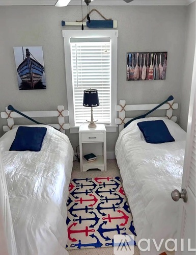 A bedroom with two beds and a rug with anchors on it.