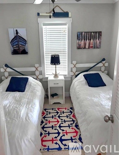 A bedroom with two beds and a rug with anchors on it.