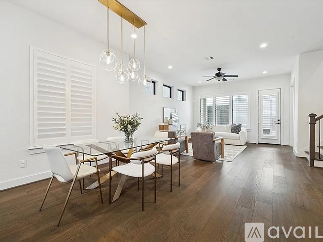 A modern dining room with a glass table and white chairs.