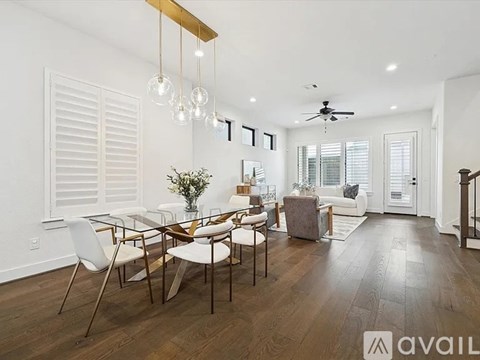 A modern dining room with a glass table and white chairs.