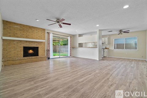A spacious living room with wood flooring and a brick fireplace.