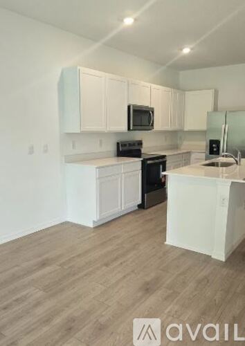 A kitchen with white cabinets and a wooden floor.