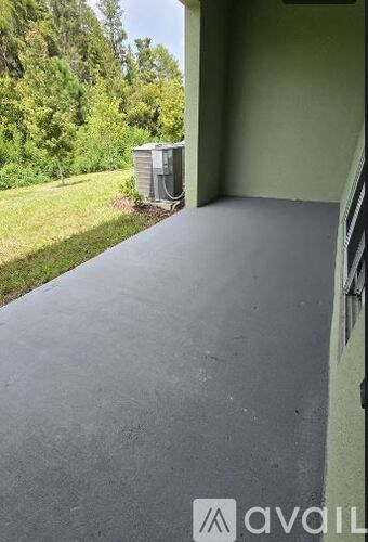 A grey covered walkway leads to a green yard.
