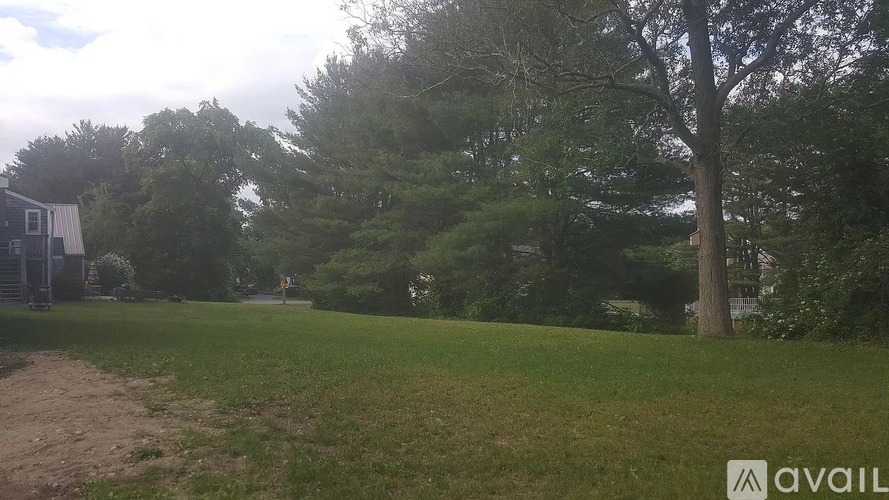 A grassy field with trees and a building in the background.
