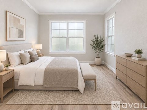 A bedroom with a large bed, a bench, and a plant.