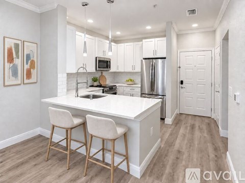A kitchen with white cabinets and a white island with two barstools.