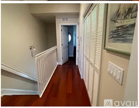 A hallway with wooden floors and white walls.