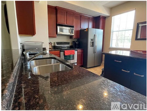 A kitchen with a granite countertop and stainless steel appliances.