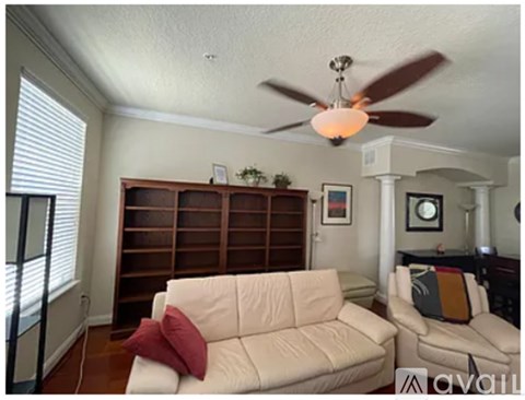 A living room with a white couch and a ceiling fan.