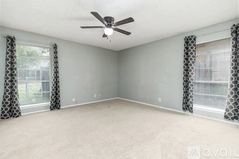 A spacious room with a ceiling fan and patterned curtains.