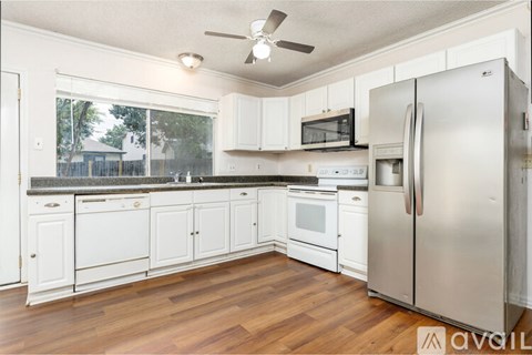 A kitchen with white cabinets and a wooden floor.