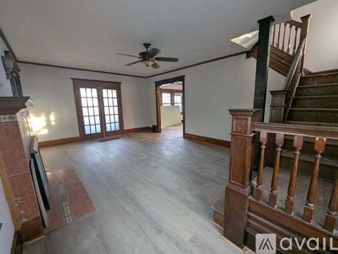 A spacious room with a wooden staircase and a ceiling fan.
