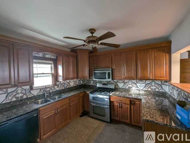 A kitchen with wooden cabinets and a black dishwasher.