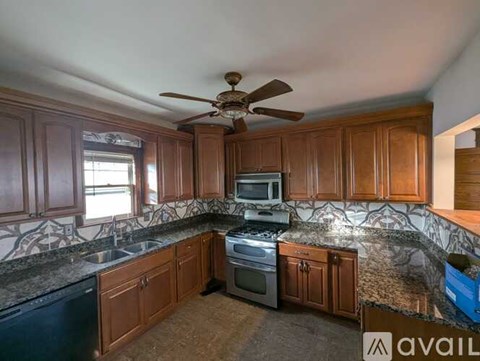 A kitchen with wooden cabinets and a black dishwasher.