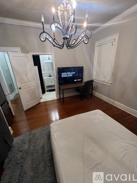A living room with a chandelier, a television, and a couch.