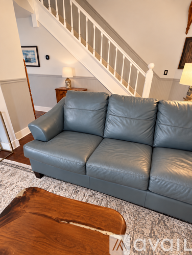 A grey leather couch in a living room with a wooden coffee table.
