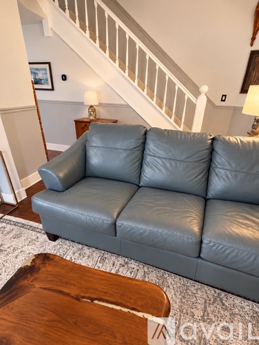 A grey leather couch in a living room with a wooden coffee table.
