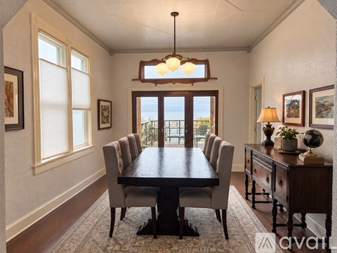A dining room with a table and chairs and a view of the ocean.