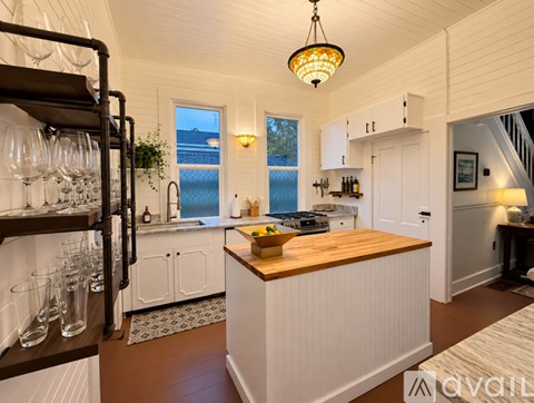 A kitchen with white cabinets and a wooden island.