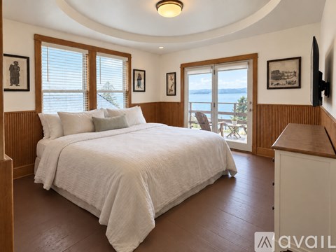 A bedroom with a large bed and a balcony overlooking the water.