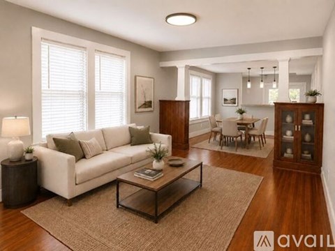 A living room with a white sofa, wooden coffee table, and a rug.