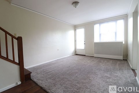 A room with a carpeted floor and a window letting in natural light.