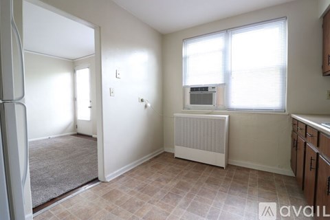 A room with a window, a radiator, and a door leading to another room.