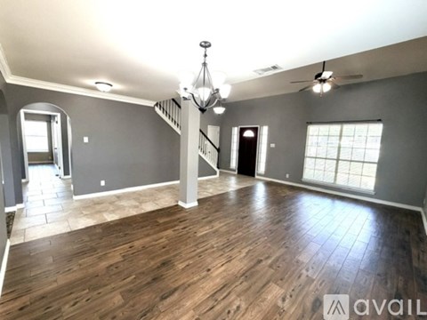 A spacious room with wooden flooring and a chandelier.