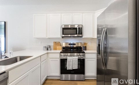 A kitchen with white cabinets and a stainless steel refrigerator.