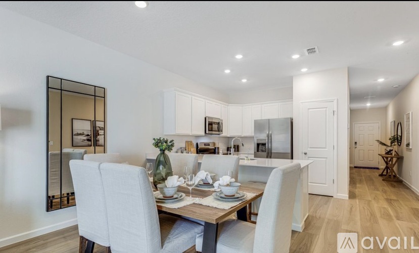 A dining area with a table set for two and a mirror on the wall.