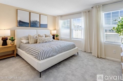 A bedroom with a large bed, a nightstand with a lamp, and a painting on the wall.
