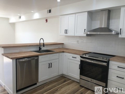 A modern kitchen with white cabinets and a wooden countertop.