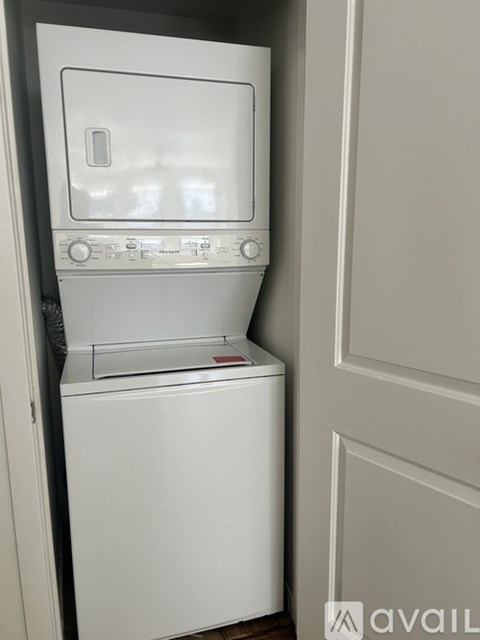 A white dishwasher is sitting in a narrow space next to a wall.