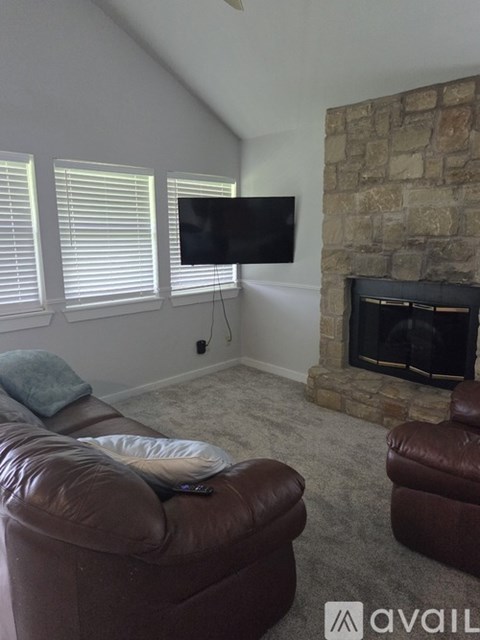 A living room with a brown leather chair and a stone fireplace.