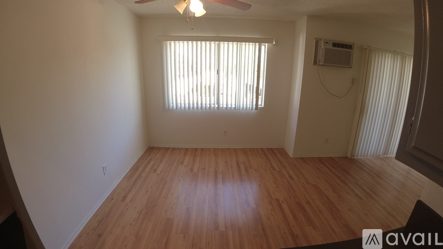 A room with wooden flooring and a window with blinds.