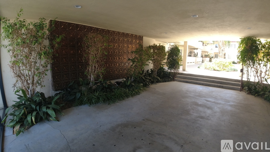 A room with a concrete floor and a wall covered in green plants.