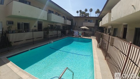 A swimming pool in a residential area surrounded by a fence.