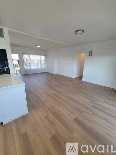 A spacious room with wooden flooring and white walls.