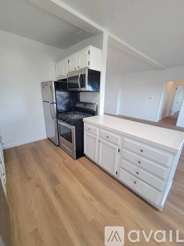 A kitchen with white cabinets and a wooden floor.