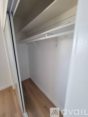 A white closet with a wooden floor and a white door.