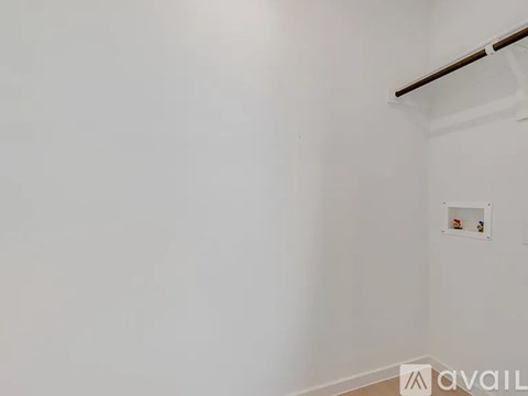 A white wall with a shelf and a small picture frame on it.