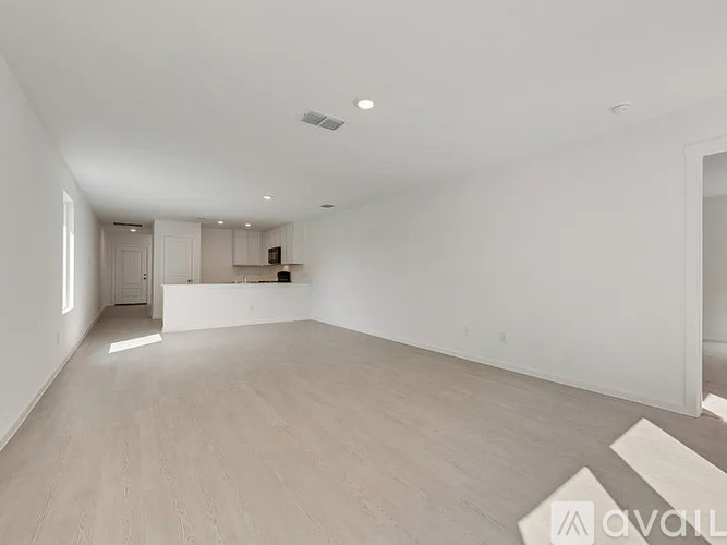 A spacious room with wooden flooring and white walls.