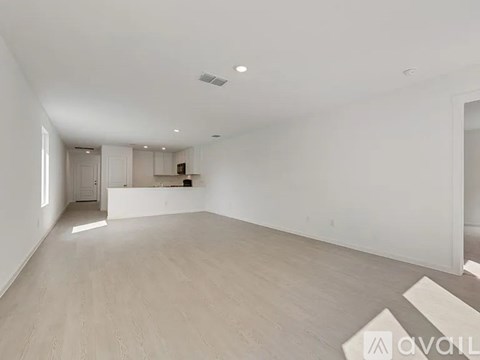 A spacious room with wooden flooring and white walls.