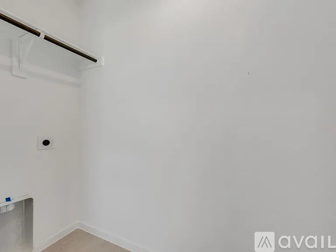 A white wall with a black pipe and a small square hole.