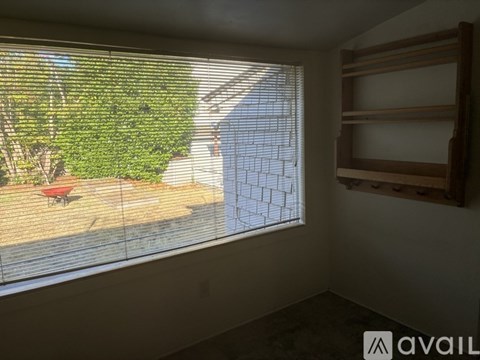 A room with a window covered in blinds, showing a patio with a table and chairs.