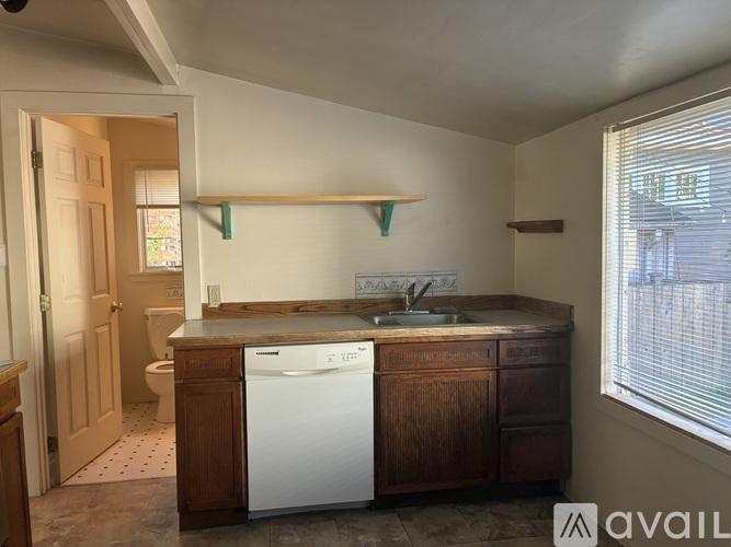 A small kitchen with a white dishwasher and wooden cabinets.