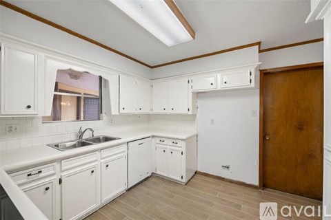 A kitchen with white cabinets and a wooden door.
