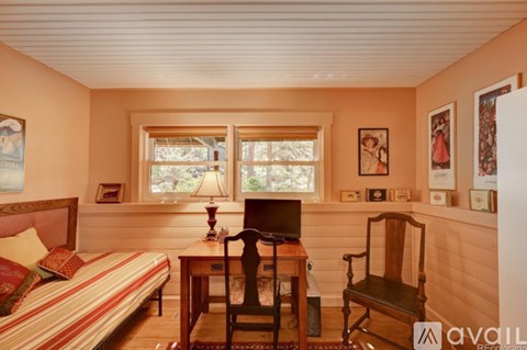 A bedroom with a bed, desk, chair, and pictures on the wall.