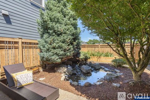 A backyard with a pond, trees, and a bench.